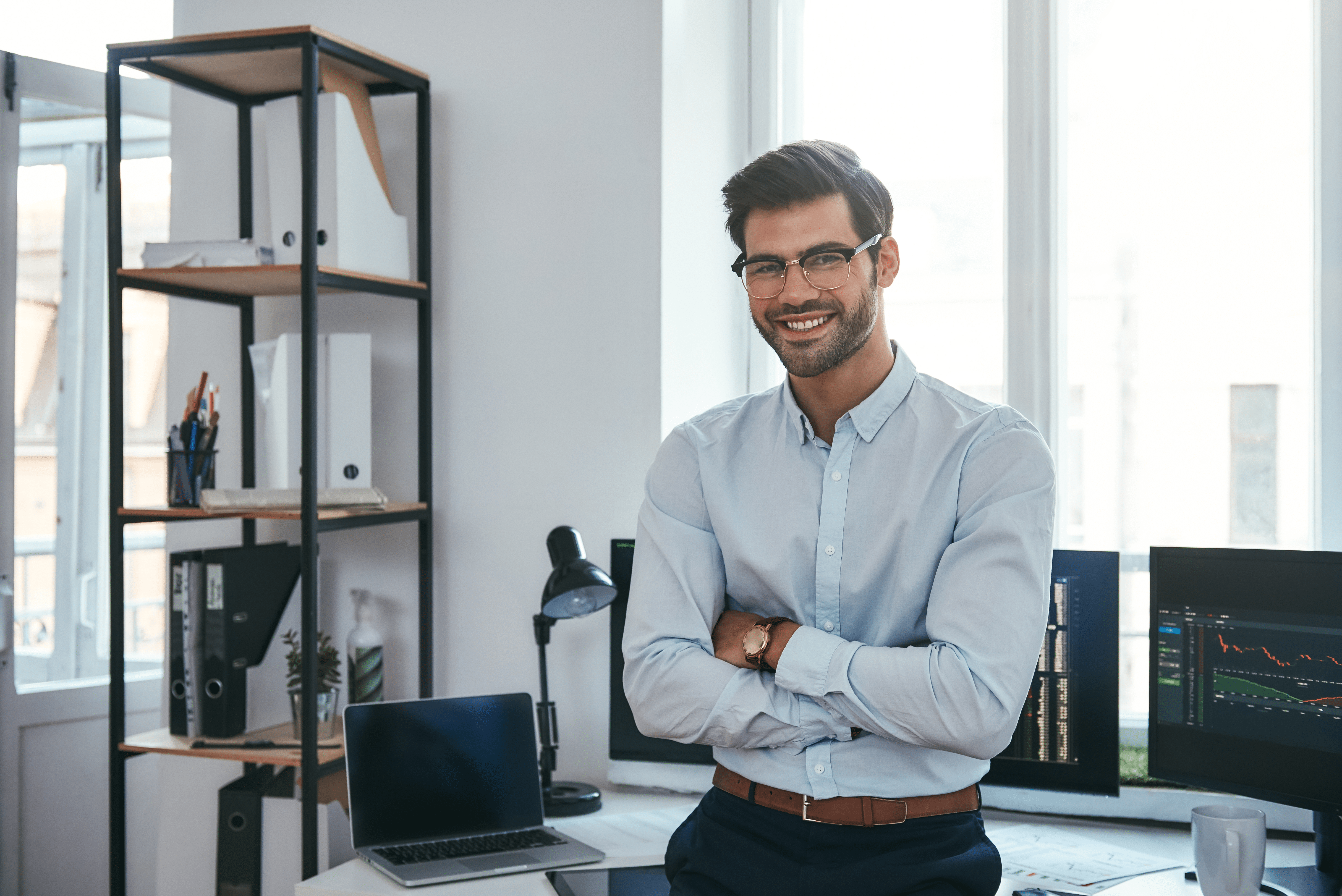 happy-trader-cheerful-businessman-formal-clothes-eyeglasses-is-keeping-arms-crossed-smiling-min